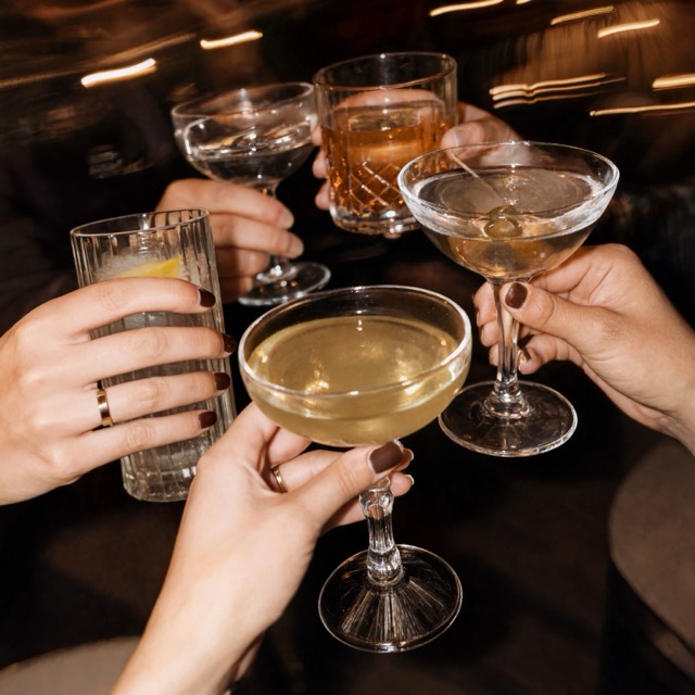 Hände stoßen mit Cocktails und Sekt an