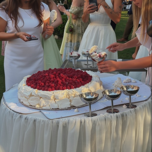 Gäste versammeln sich um die Hochzeitstorte mit frischen Himbeeren